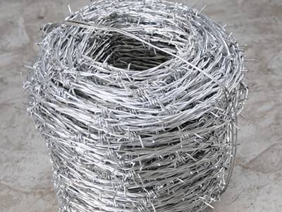 A roll of hot dipped galvanized barbed wire on the ground.