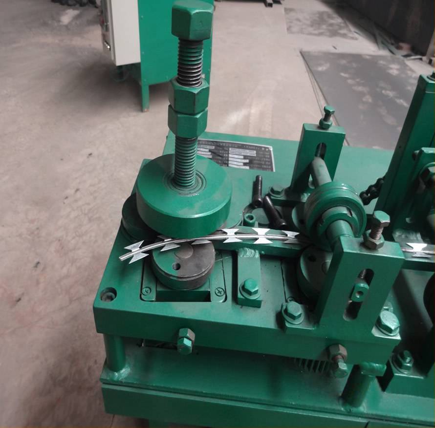 A green color razor wire machine is producing the razor wire in the workshop.