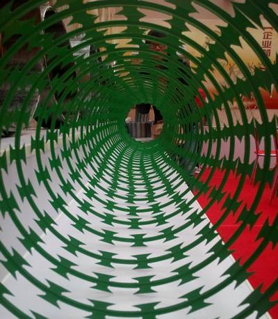 A stretching coil of PVC coated concertina razor wire in green.