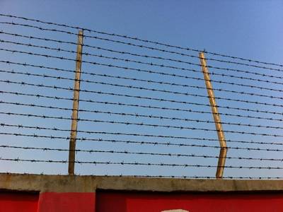 Several lines of barbed wire are attached onto the post at the top of wall.