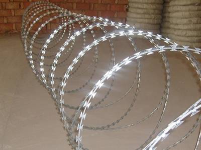 A roll of galvanized double spiral razor wire on the ground.
