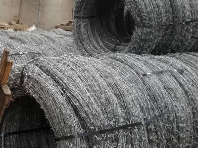 Several rolls of concertina barbed wire fastened with bailing strips in the warehouse.