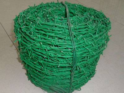A roll of green color PVC coated barbed wire on the ground.