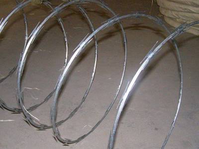 A roll of single spiral concertina razor wires on the ground.